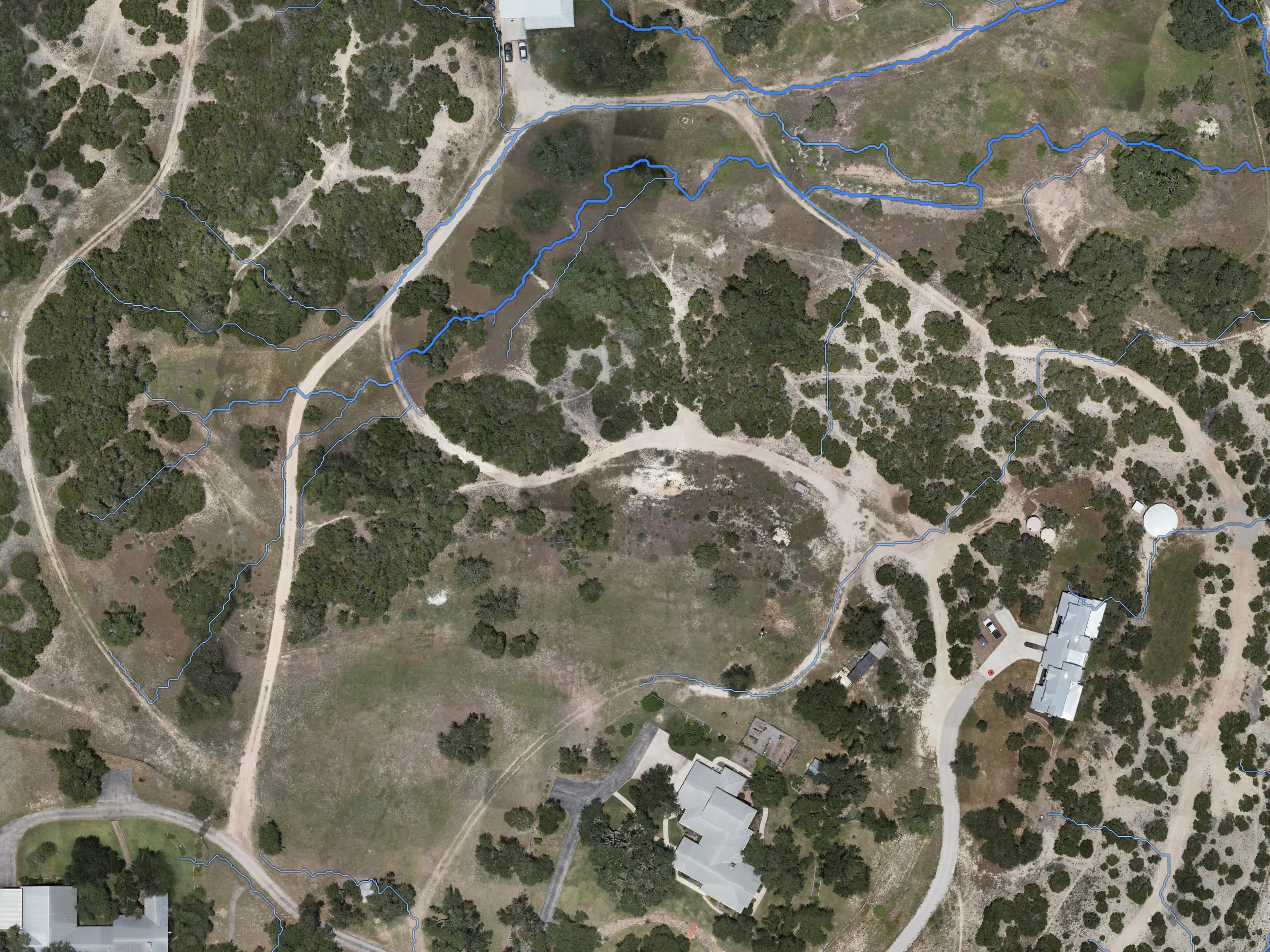 Modeled drainage lines in blue over the August 2026 photo of our showcase ranch, from the July 2026 LiDAR.
